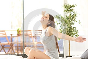 Happy woman waking up outstretching in bed photo