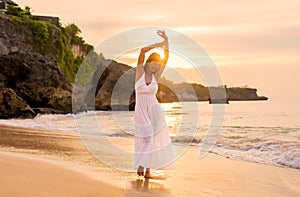 Happy woman walking on beach at sunset
