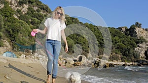 Happy woman walking with dog at the beach.