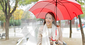 Happy woman walking holding an umbrella under the rain