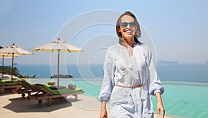 Happy woman walking over infinity edge pool