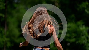 Happy woman is walking in park, running and turning to camera, smiling flirtatiously