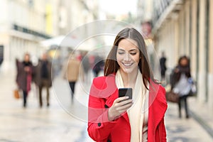 Happy woman walking using a cellphone in the street