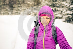 Happy woman walking in winter forest with backpack