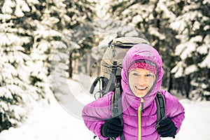 Happy woman walking in winter forest with backpack