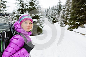 Happy woman walking in winter forest with backpack