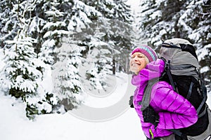 Happy woman walking in winter forest with backpack