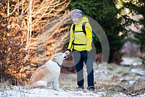 Happy woman walking in winter forest with dog