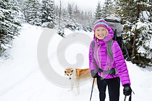Happy woman walking in winter forest with dog