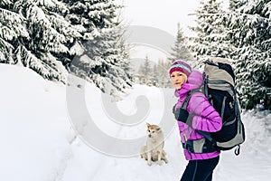Happy woman walking in winter forest with dog