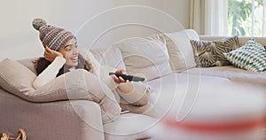 Happy woman in warm clothing lying on sofa watching television 4K 4k