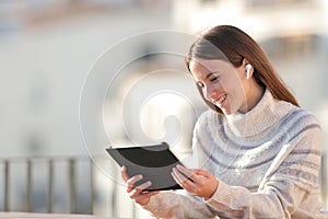 Happy woman watching media on tablet in a balcony