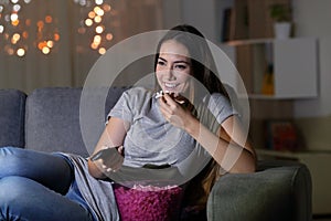 Happy woman watching tv in the night at home photo