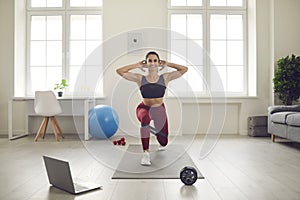 Happy woman watching workout lesson and doing forward lunges with resistance band