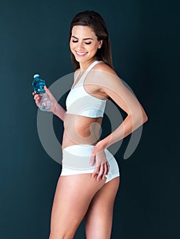 Happy woman, water bottle and bum for body diet, health and wellness against a studio background. Female person or