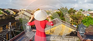 Happy woman wearing Ao Dai Vietnamese dress, traveler sightseeing view at rooftop in Hoi An ancient town. landmark and popular for