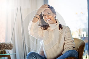 Happy woman wearing casual clothes while sitting on the sofa at home