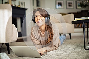 Happy woman wearing headphone and using laptop at home