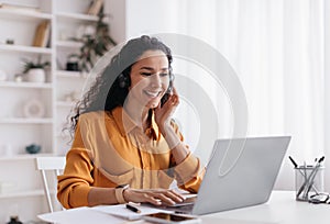 Happy Woman Wearing Headset Video Calling On Laptop At Workplace