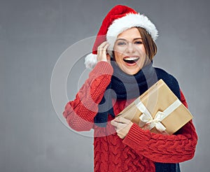 Happy woman wearing knitted sweater and Santa hat holding Christmass gift