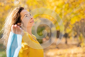 Happy woman wearing protective mask in autumn park