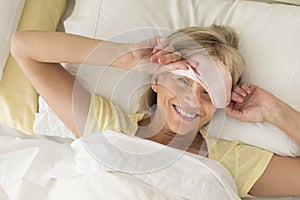 Happy Woman Wearing Sleep Mask On Bed