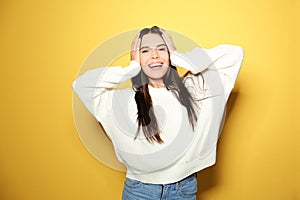 Happy woman wearing warm sweater on yellow background