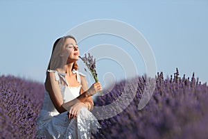 Woman smelling bouquet of lavender flowers in a field