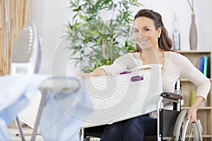 happy woman in wheelchair carrying basket laundry
