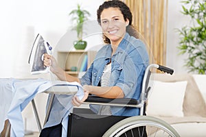 happy woman in wheelchair ironing at home