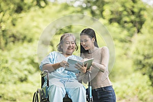 Happy Woman in a wheelchair reading a book with her daughter