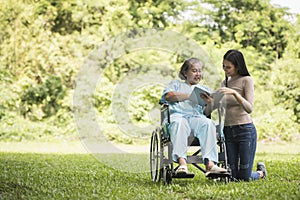 Happy Woman in a wheelchair reading a book with her daughter