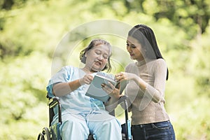 Happy Woman in a wheelchair reading a book with her daughter