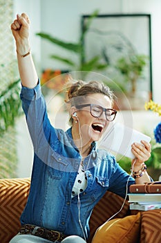 Happy woman with white headphones and tablet PC rejoicing