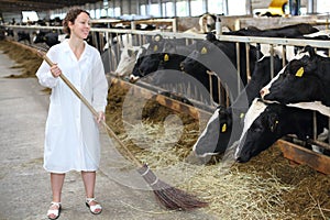 Happy woman in white robe sweeps floor in large