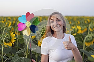 Happy woman with windmill toy on the sunflower field. Showing class. Alternative energy. Green energy concept