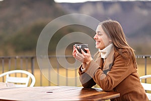 Happy woman in winter drinking in a terrace