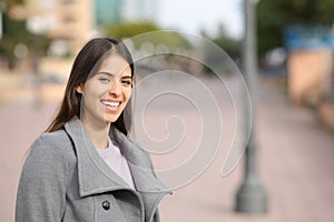 Happy woman in winter laughing in the street looks at you