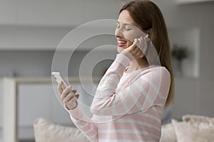 Happy woman with wireless earphone in ear listening to music