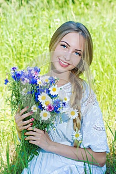 Happy woman wit bouquet of chamomiles and cornflowers