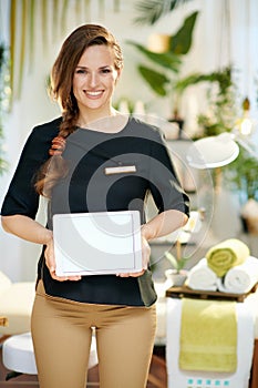 Happy woman worker in beauty studio showing tablet PC