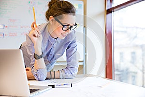 Happy woman working with blueprint near the window in office