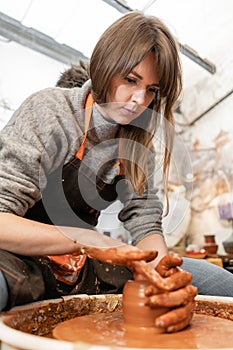 Happy woman working on potter wheel in pottery workshop. Family business shop sculpts pot from clay view top.