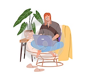 Happy woman works from home, sitting in cozy armchair at laptop computer. Young freelancer, remote worker working