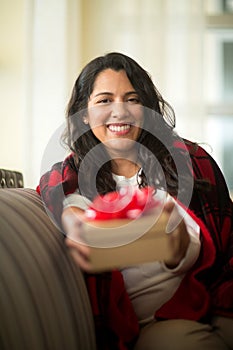 Happy woman wrapped in a cozy blanket holding a gift.