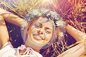 Happy woman in wreath of flowers lying on straw