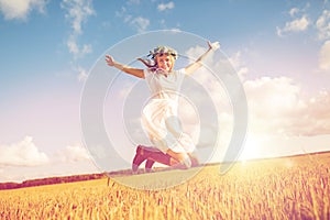 Happy woman in wreath jumping on cereal field