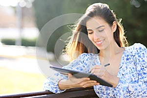 Happy woman writing on tablet with pen