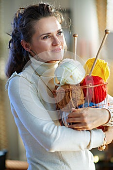 Happy woman with yarn in modern living room in sunny winter day