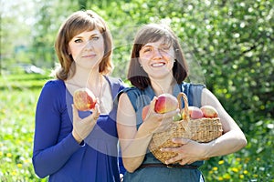 Happy women with apples in orchard